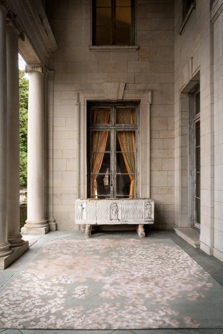 Colonnade at Alder Manor with a carved marble trough beneath a tall window and a pale floral rug